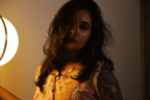 Modelling image of Reshma Das. Intriguing face of a lady with open hair, covering half of the face, standing in a warm dim lighted setting